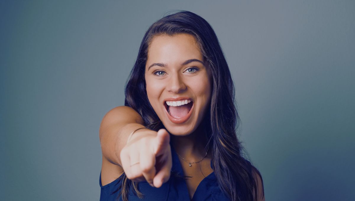 dark haired woman with blue eyes pointing at you